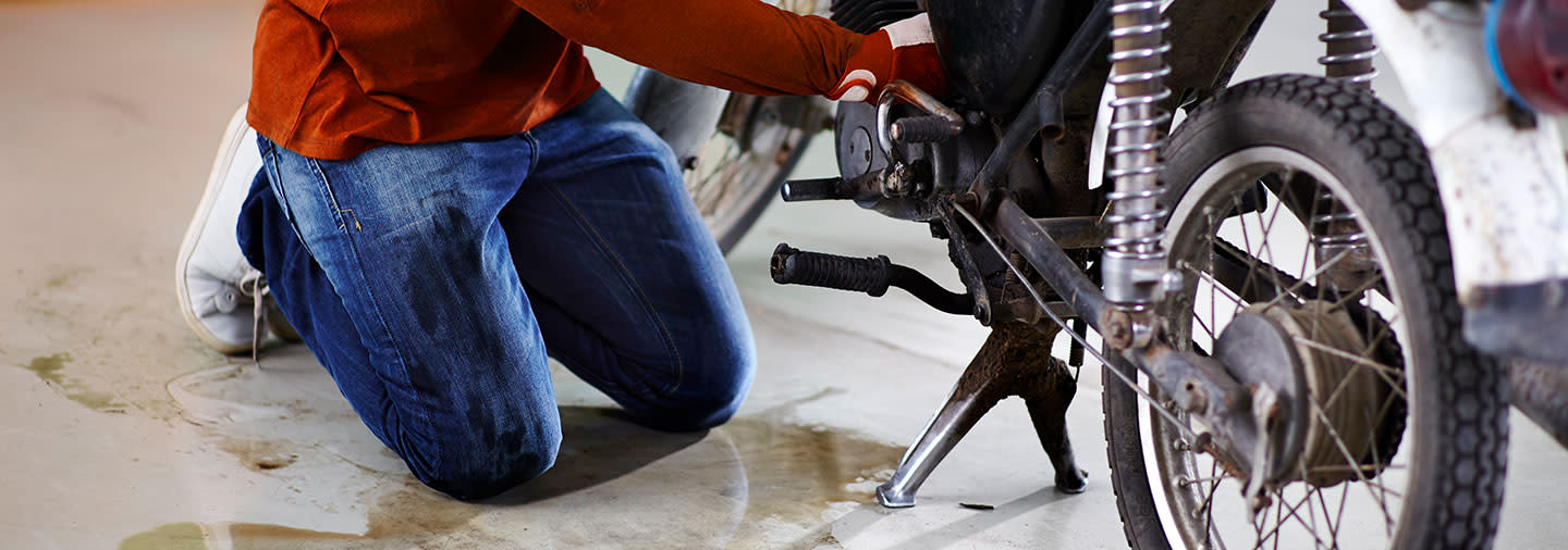 A man repairing a motorcyle on the ground