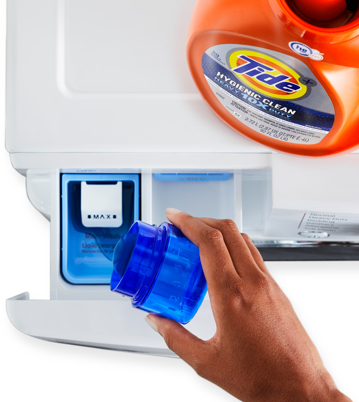 A hand pouring liquid laundry detergent into the dispenser