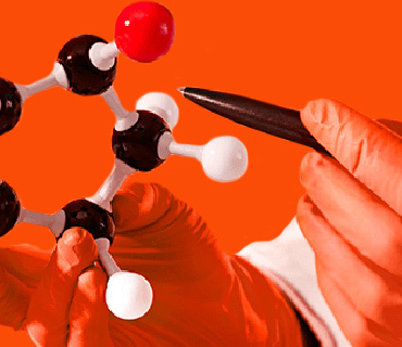 Two hands in orange gloves putting together an atomic model