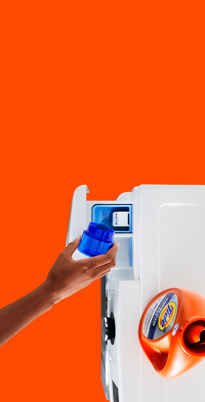 A person pouring Tide liquid detergent into the detergent dispenser