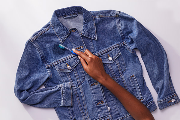 A person brushing off excess from denim jacket