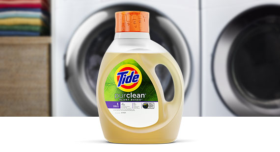 A bottle of Tide purclean plant-based liquid laundry detergent in front of a white washing machine