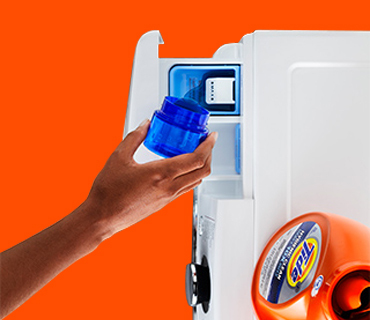 A hand pouring Tide liquid laundry detergent into the dispenser drawer of a washing machine