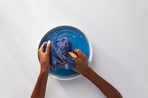 A person is soaking denim into soaking solution