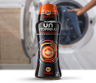 Downy Unstopables with Tide Original scent in front of a white washing machine