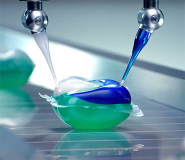 A Tide PODS capsule being filled up with colorful liquid components