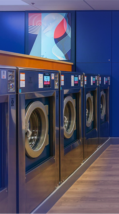 A self-service laundromat with two rows of washing-machines on the sides