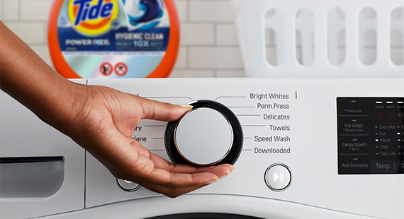 A hand showing how to select the wash cycle and water temperature on your washing machine 