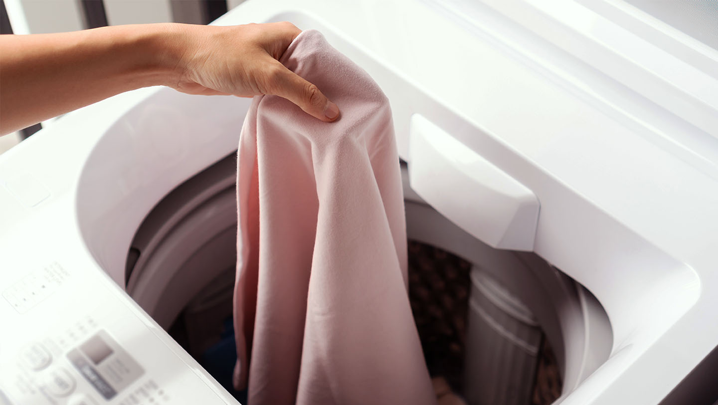 A person holding 2 Tide PODS washing capsules