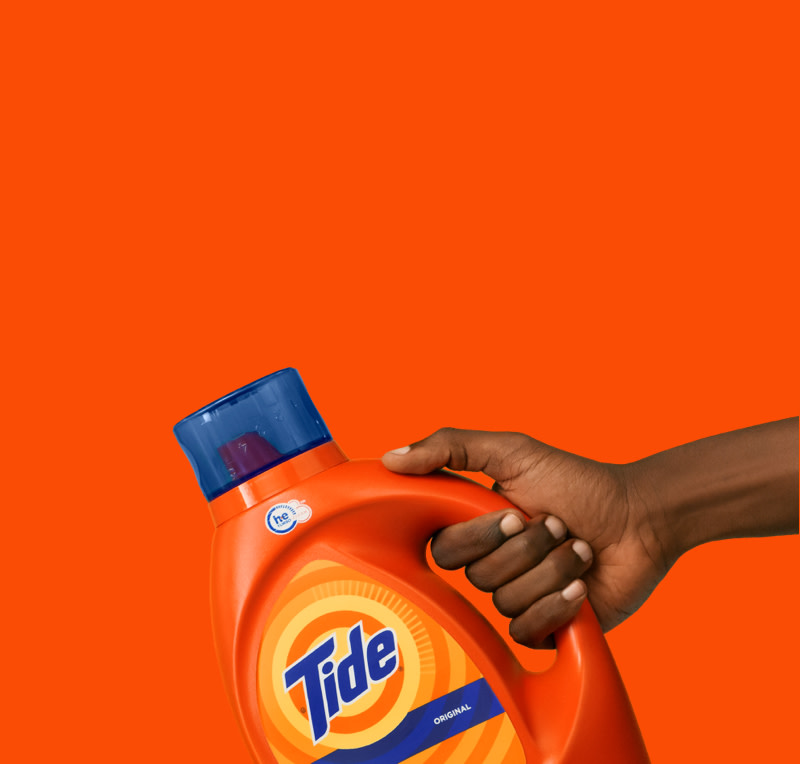 A hand holding a Tide Original liquid laundry detergent bottle