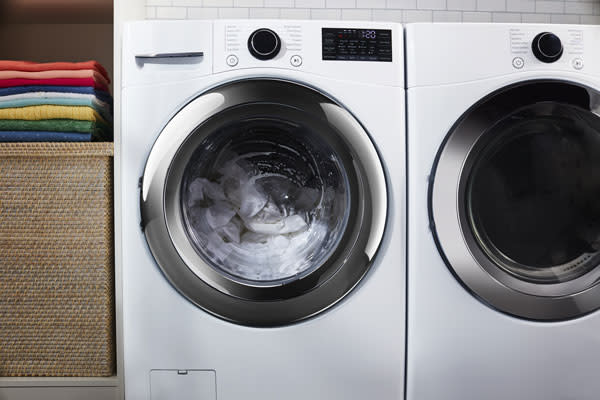 A person unloading white clothes into the washing machine drum