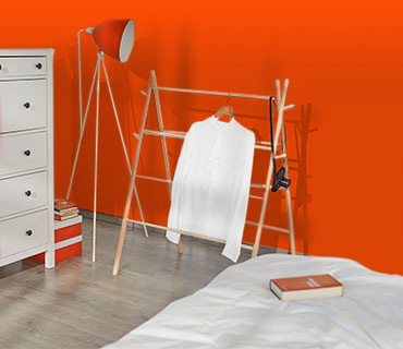 A white shirt hung out to dry on a wooden dryer in a bedroom