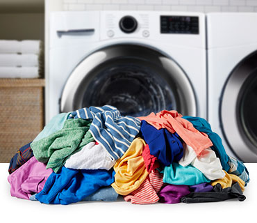 A pile of colorful garments in front of a washer