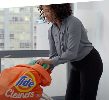 A woman packing clothes into a Tide Cleaners bag