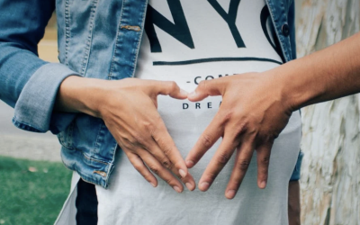 heart hand signal on top of a pregnant belly