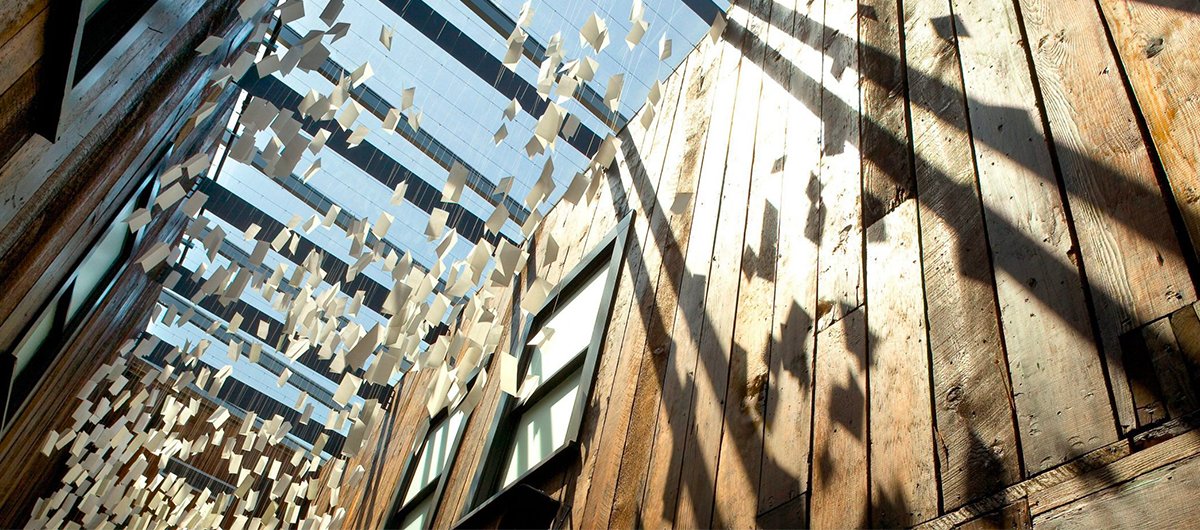 Letter Cloud by artists Erin Shie Palmer and Susie Kozawa hangs within the historic west lightwell of the building that once provided light and ventilation to interior apartment rooms for pioneer Asian laborers.