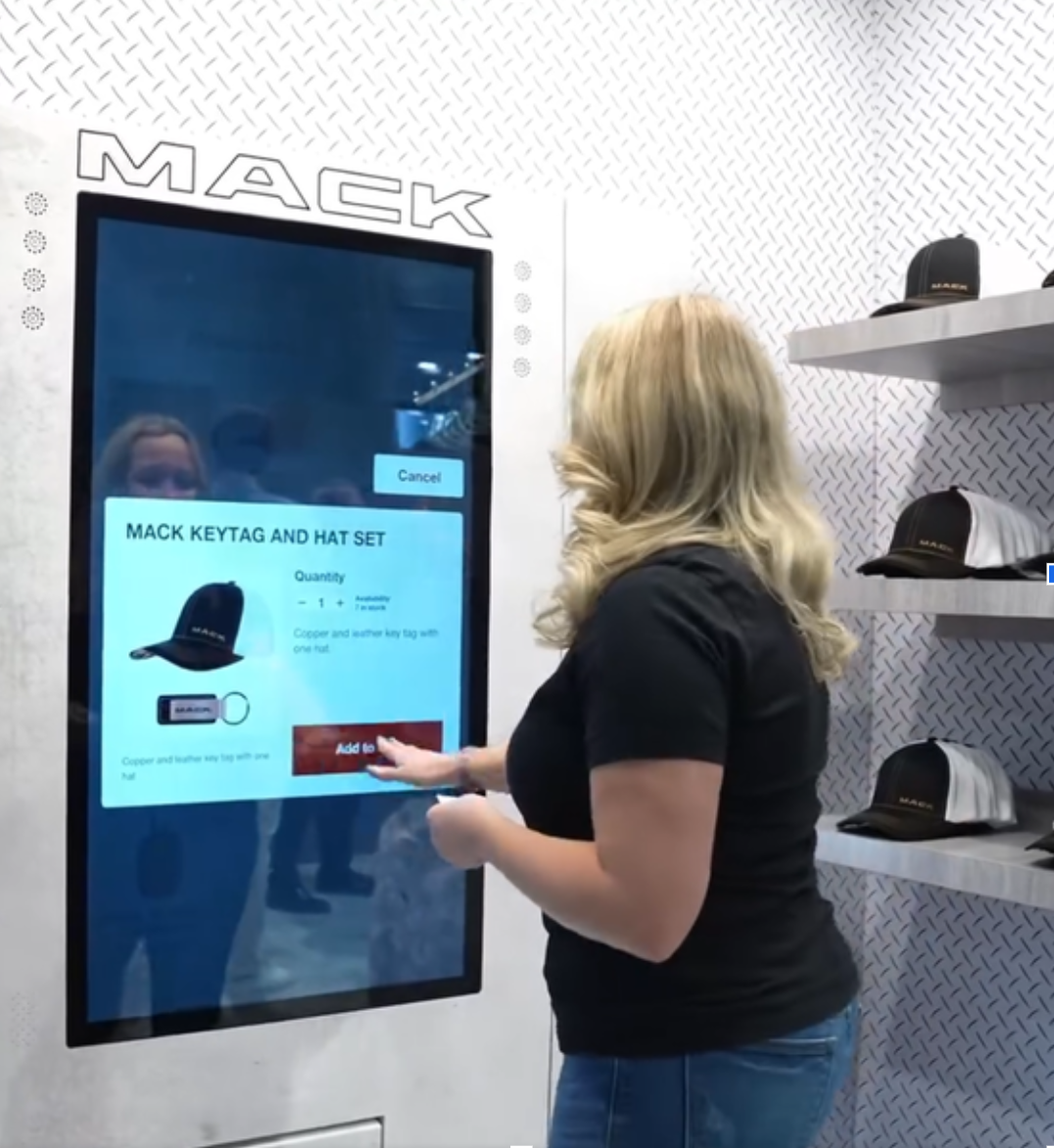 Person getting Mack Truck merchandise from a silver vending machine. 