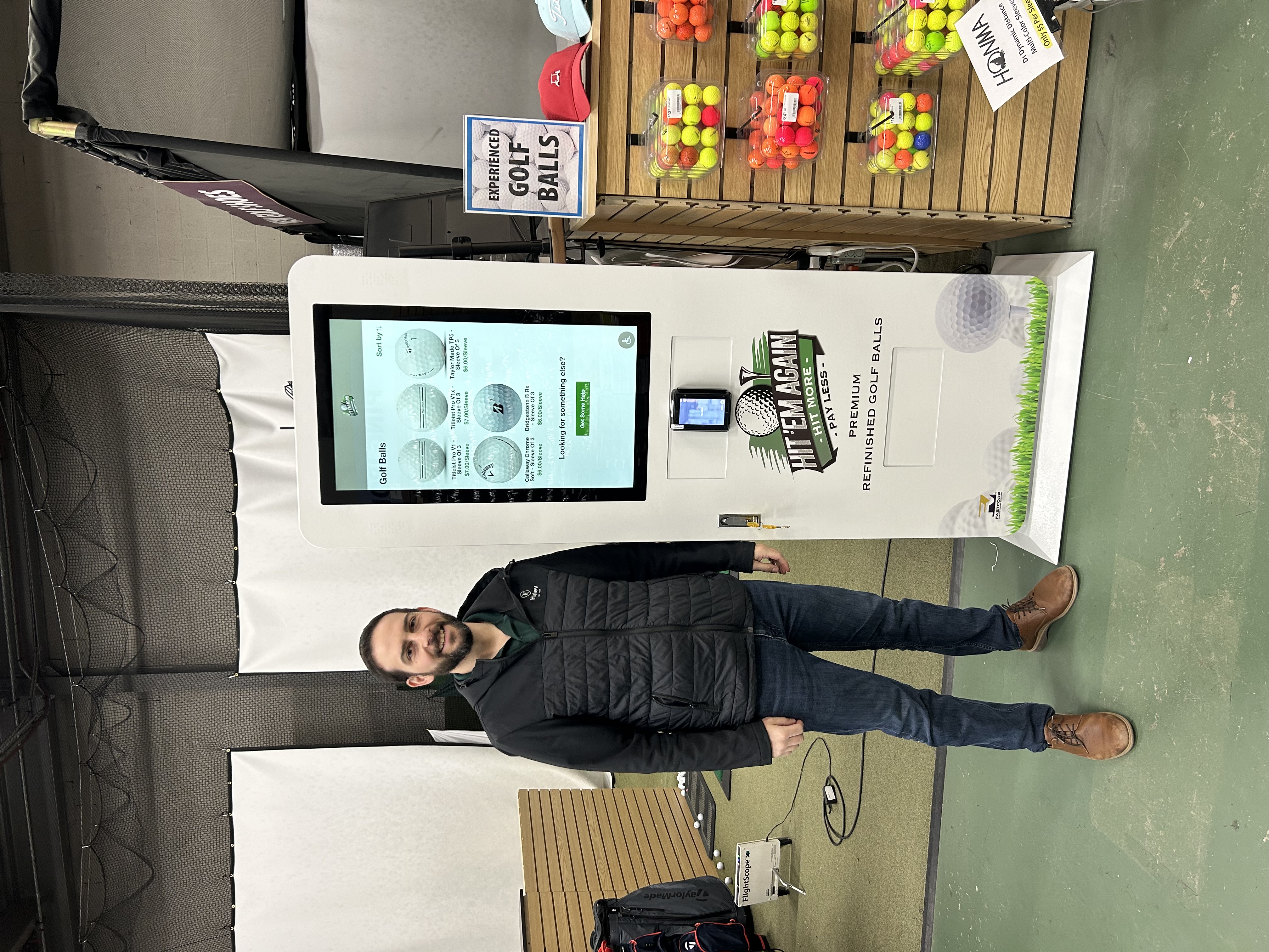 Photo of a happy person standing next to a vending machine selling golf balls.
