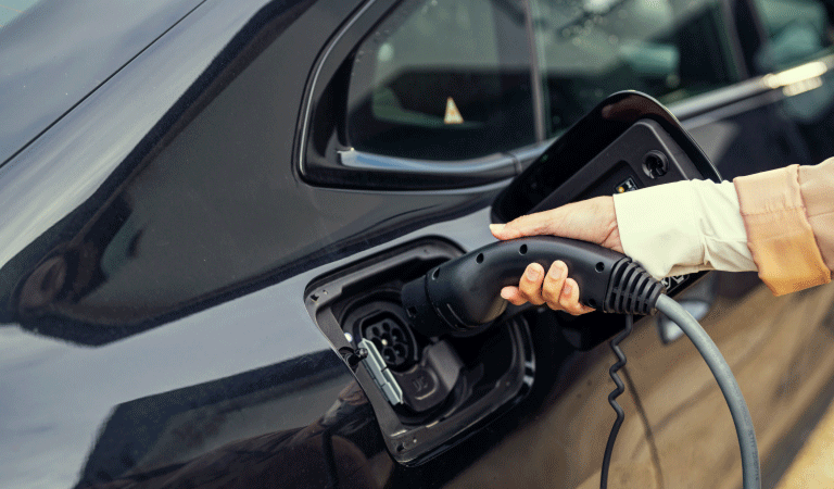 Hand die oplaadstekker in elektrische auto steekt.