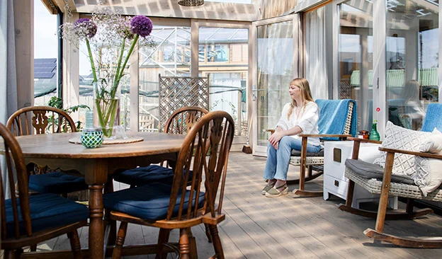 Marjolein Jonker zit in de glazen uitbouw van haar tiny house.