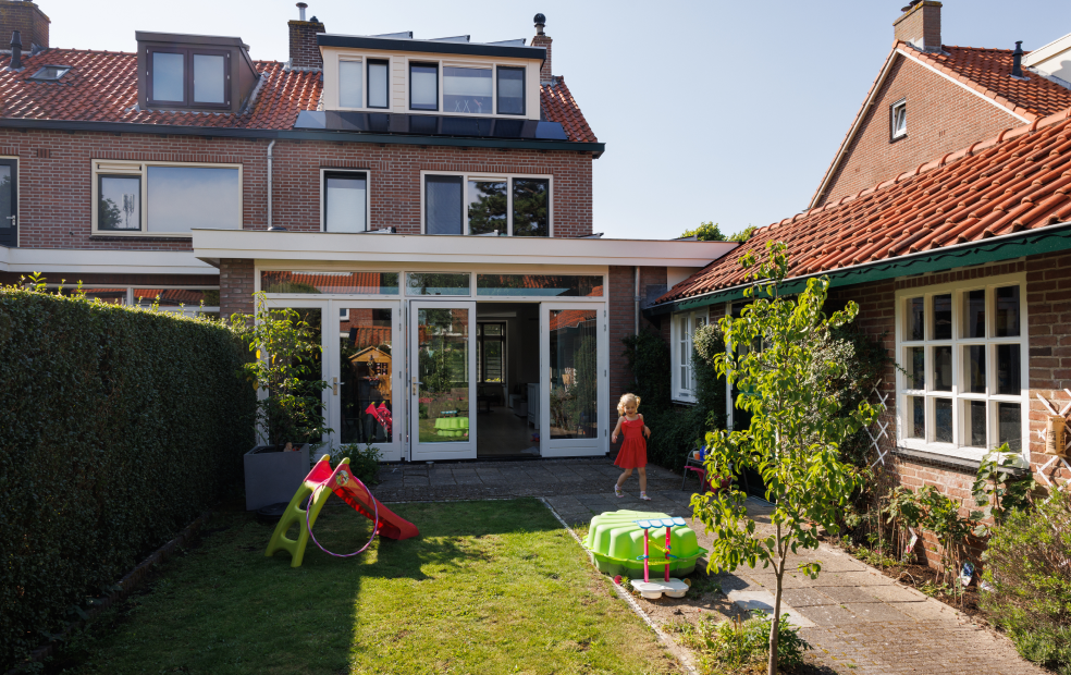 Achtertuin van het huis van Rob en Imke met zicht op de achterzijde van het grotere huis dat zij kochten.