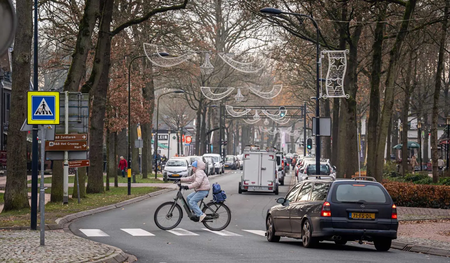 Drukke verkeersweg in Zuidlaren met auto's en een fietser die het zebrapad oversteekt.