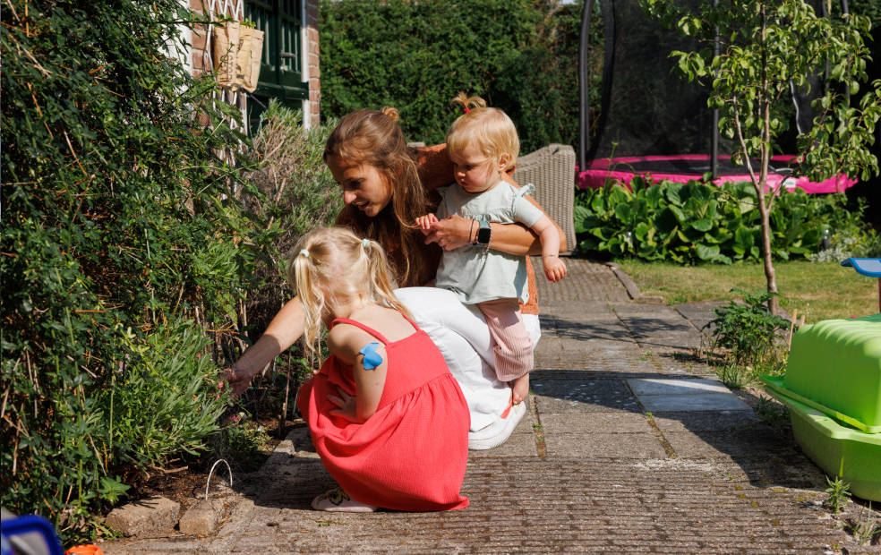 Imke met haar twee dochters in de zonnige achtertuin van hun huis.