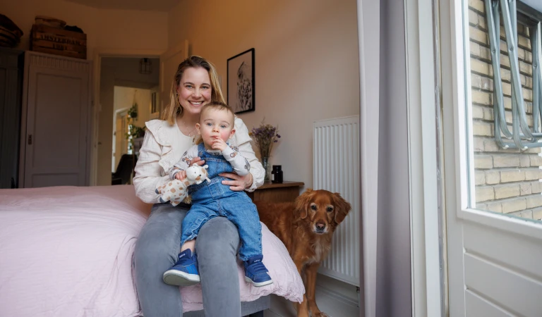 Laura met haar zoontje Otis op schoot in haar slaapkamer.