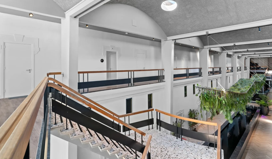 De voormalige hal met lokalen en de centrale trap, waar vroeger lokale op uit kwamen. Nu zijn het appartementen.