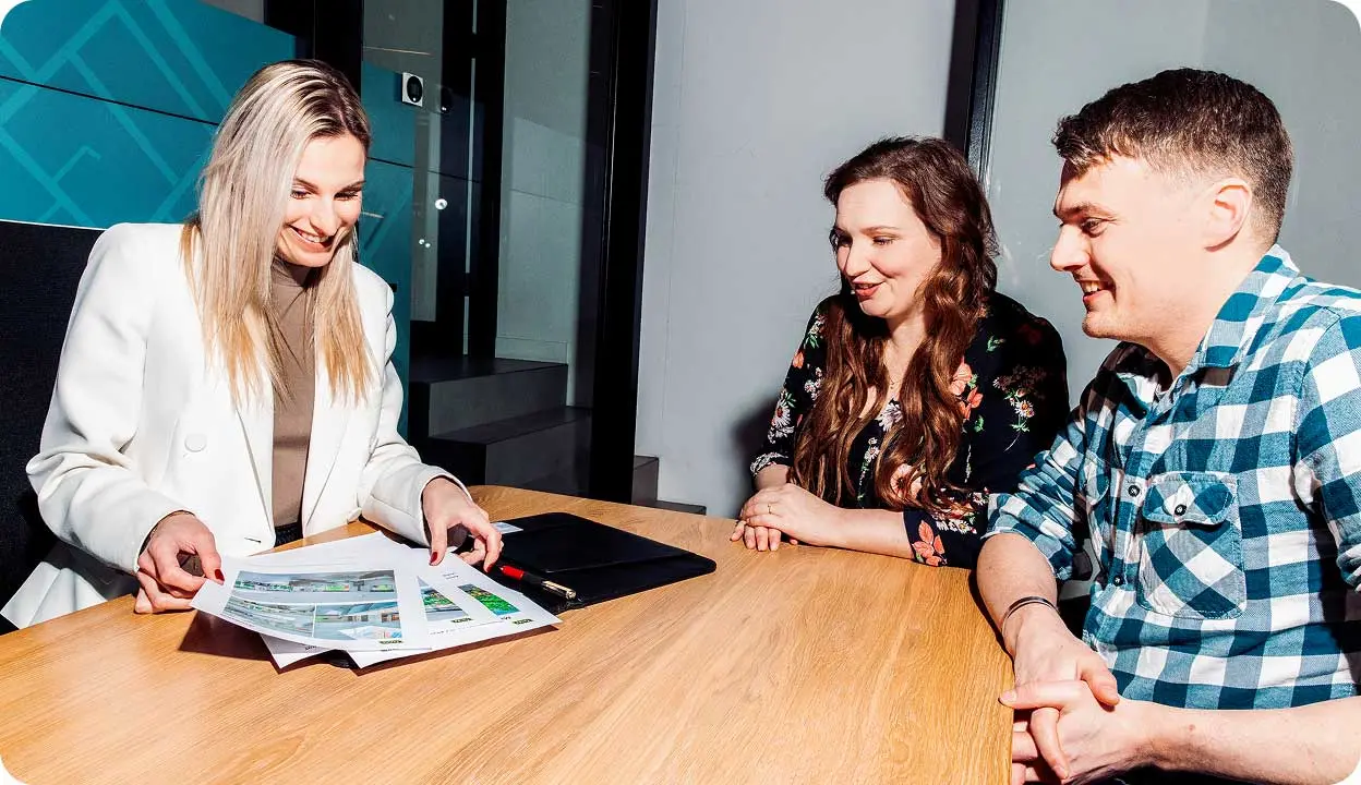 Makelaar Stephanie neemt op haar kantoor, aan tafel met Floor en Rick, de benodigde papieren voor het huis door. 
