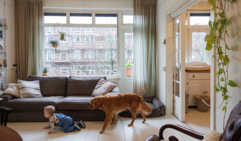 Zoontje Otis en hond Dexter kruipen samen door de huiskamer van het Amsterdamse appartement van Laura.