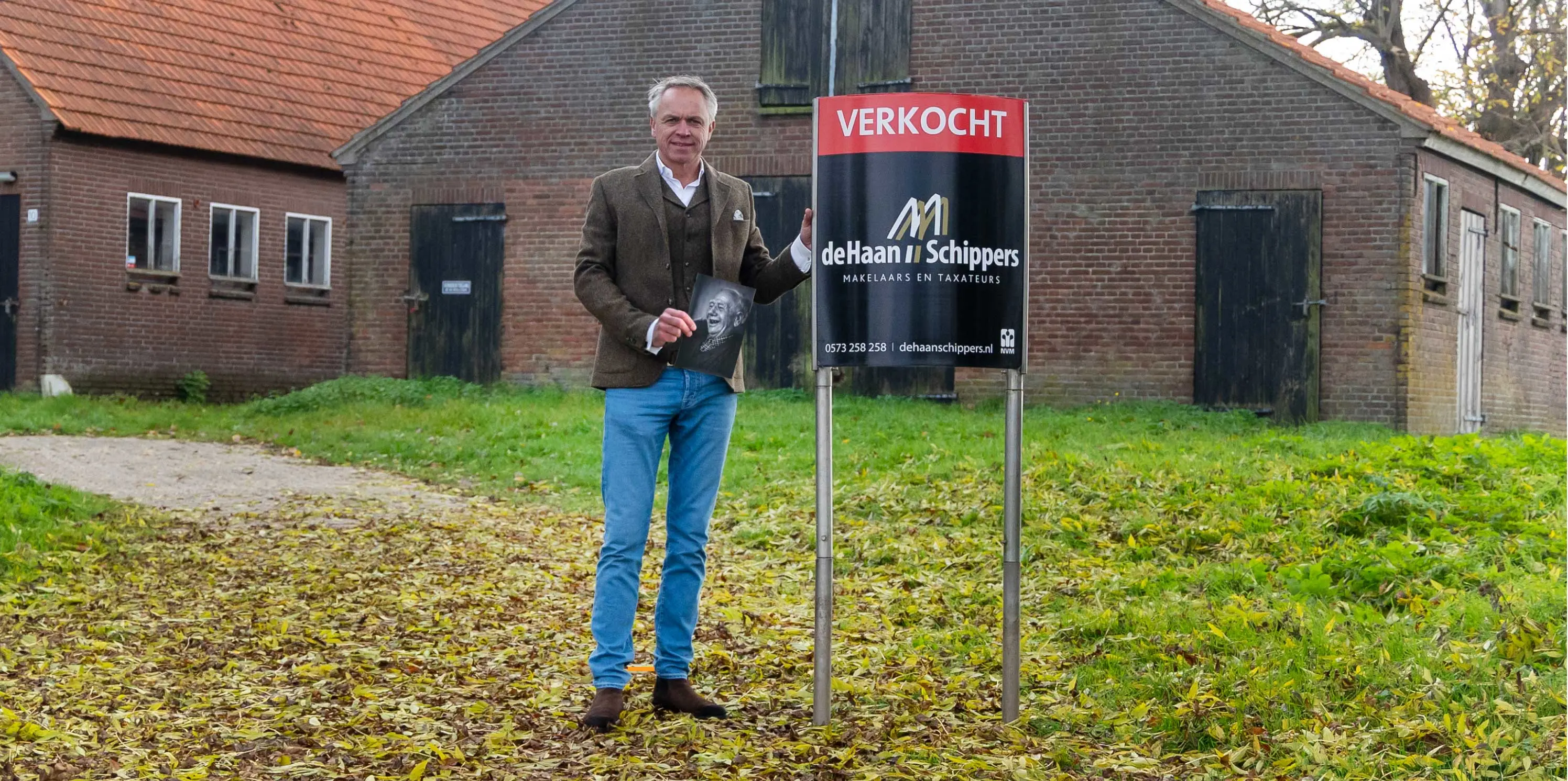 Makelaar Marcel Schippers naast het Verkocht-bord bij wederopbouwboerderij 't Heyendaal in Brummen.