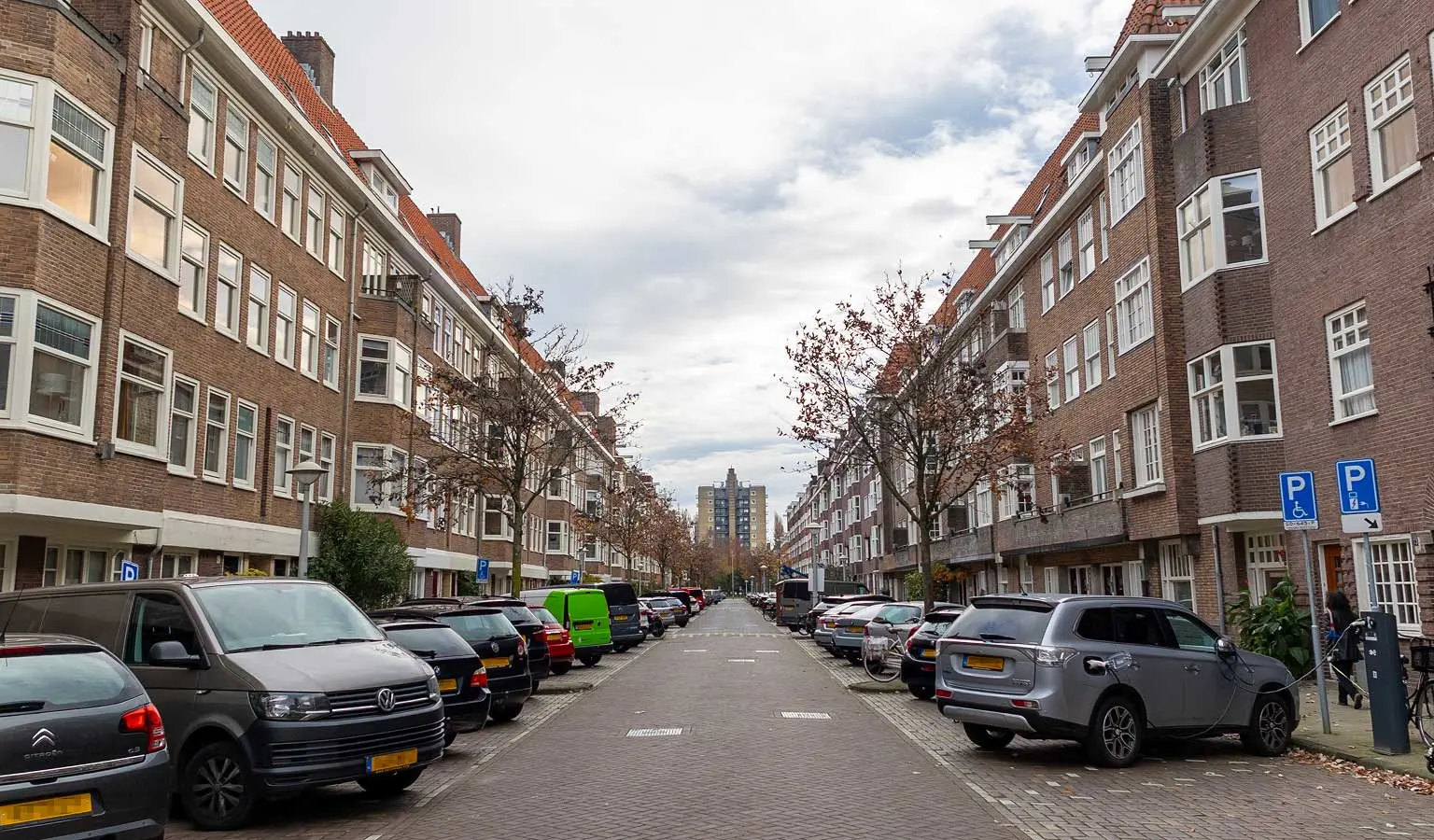 Straat in de Rivierenbuurt in Amsterdam met aan weerszijden appartementen en geparkeerde auto's.