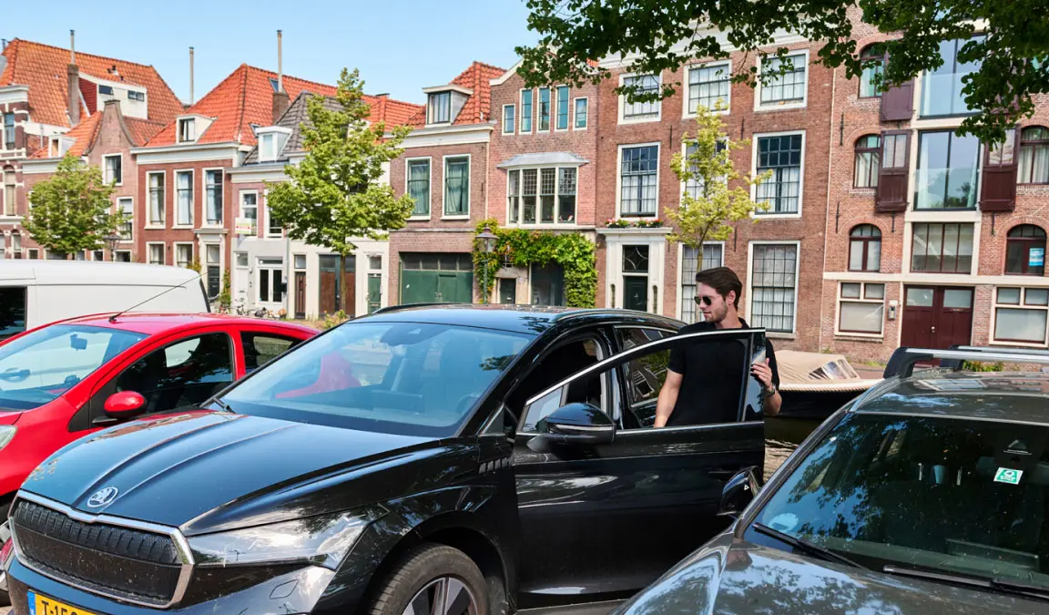 Martijn stapt in zijn zwarte auto voor de deur in Leiden.