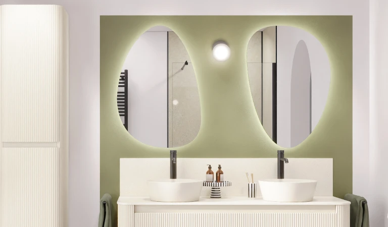 Witte, ronde wasbekkens en ovaalvormige spiegels tegen een zachtgroene achterwand.