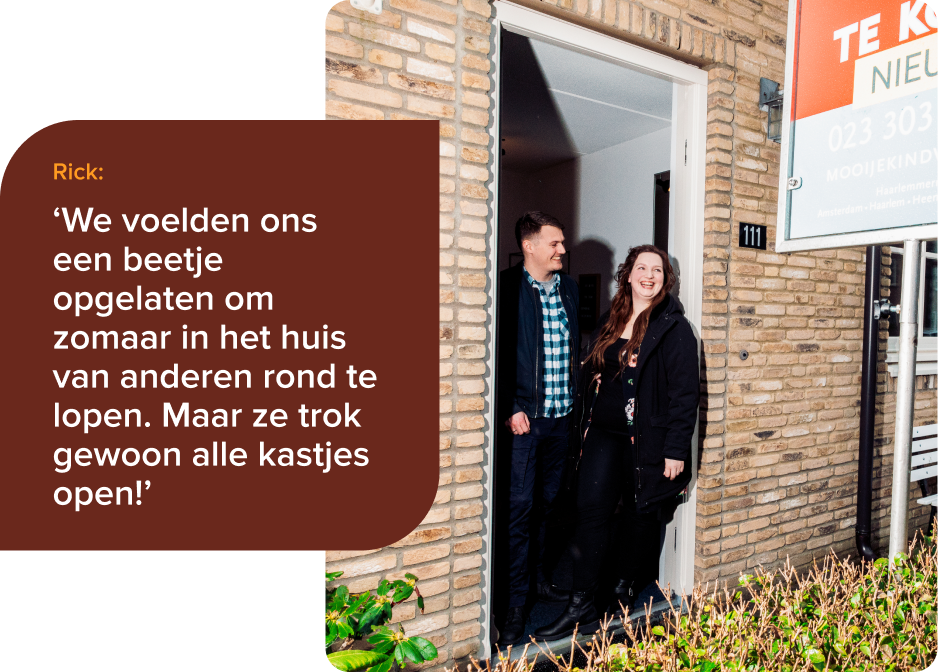 Rick en Floor staan in de deuropening van hun nieuwe huis, met op de voorgrond nog een deel van het tekoopbord in beeld. 