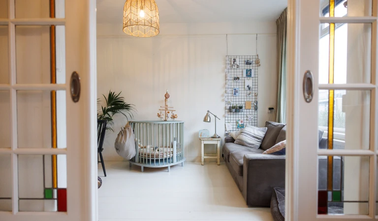 Doorkijkje via de schuifdeuren vanuit de slaapkamer van haar zoontje naar de huiskamer.