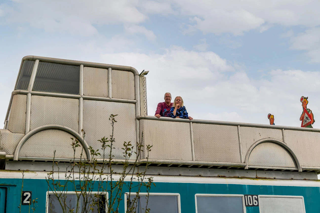 Verkoper Frank Appel staat samen met zijn vriendin in een nagemaakte truck, die bovenop de blauwe trein is gemonteerd als dakterras. 