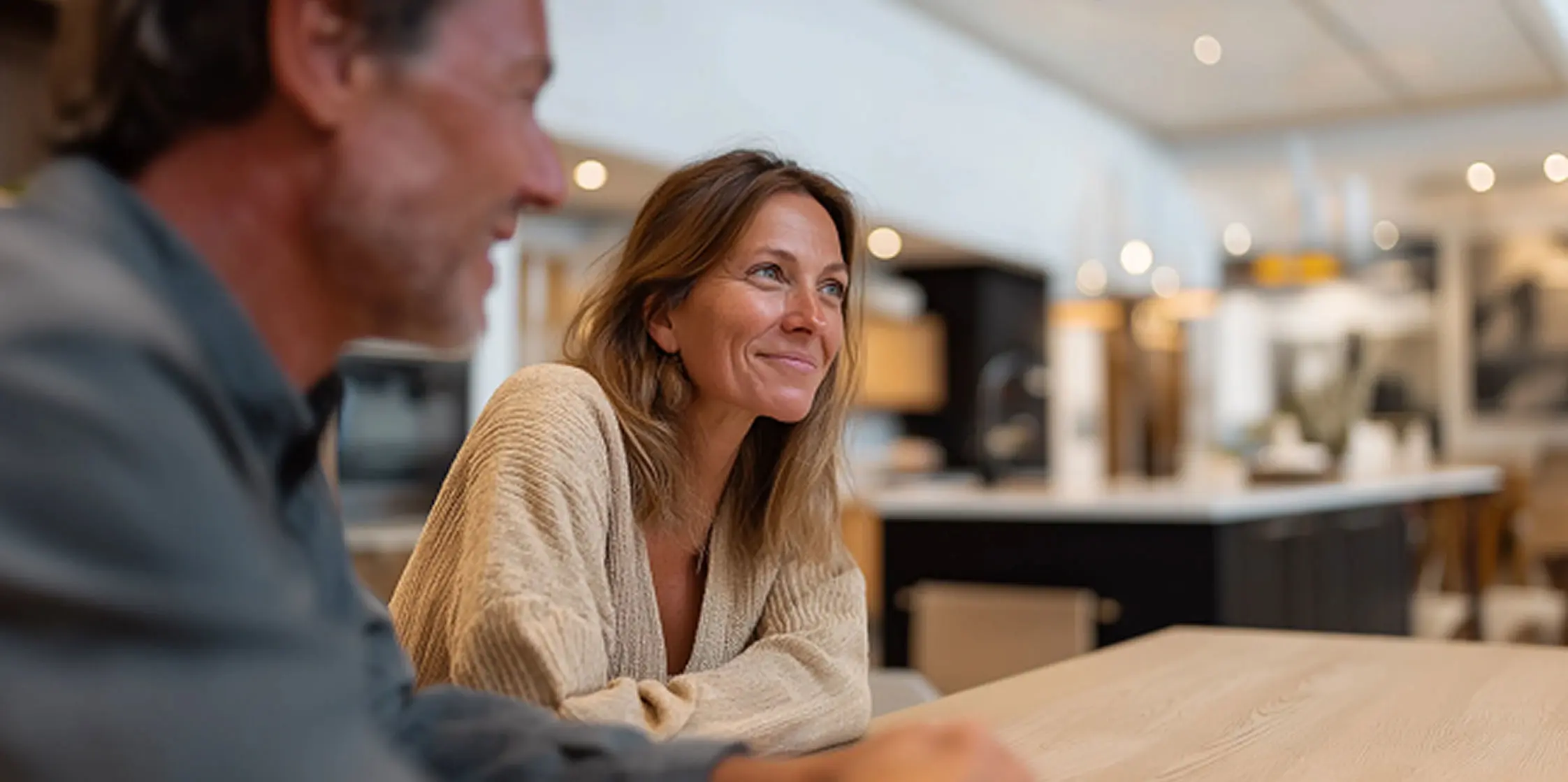 Vrouw en man aan tafel bij een keukenleverancier voor een adviesgesprek.