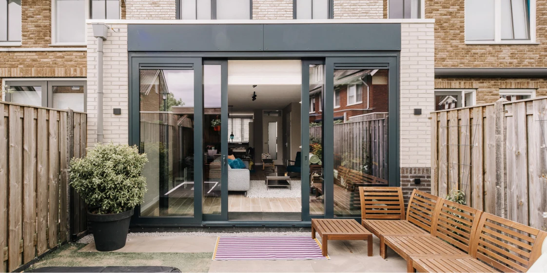 Een serre aan de achterkant van een modern huis met een grijze omhuizing.