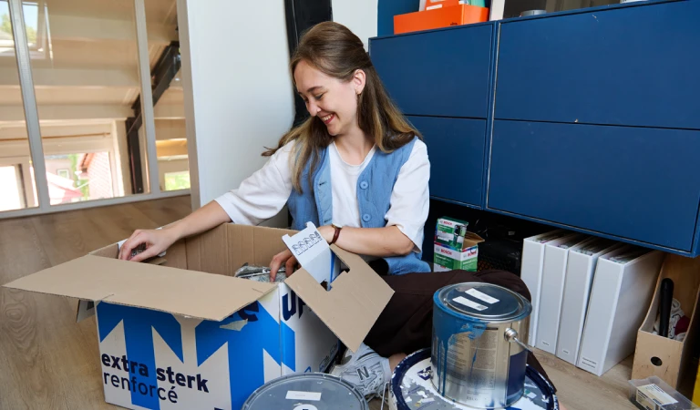 Starter Myrhte is bezig met verhuisdozen uitpakken in een van de kamers boven.