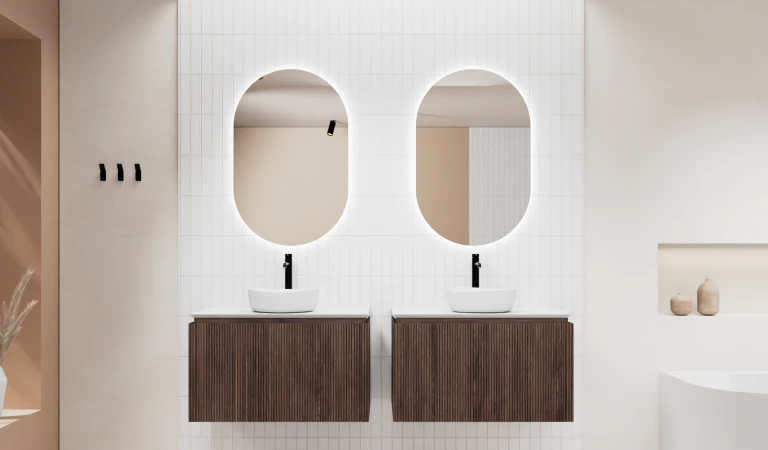 Wasbekkens met houten onderkastjes en ronde spiegels tegen een witte Cloud Dancer-achtergrond. 