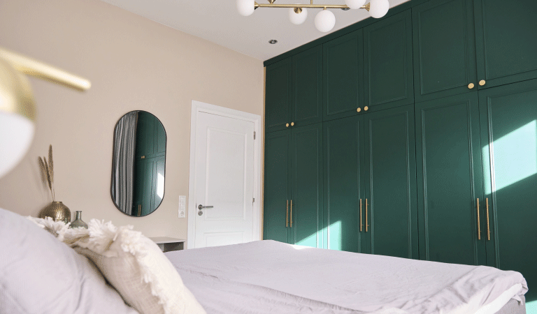 De verbouwde slaapkamer van Djoeke en Goffe-Jan. Donkergroene inbouwkasten tegen de wand, tegenover het bed, zorgen voor veel bergruimte.