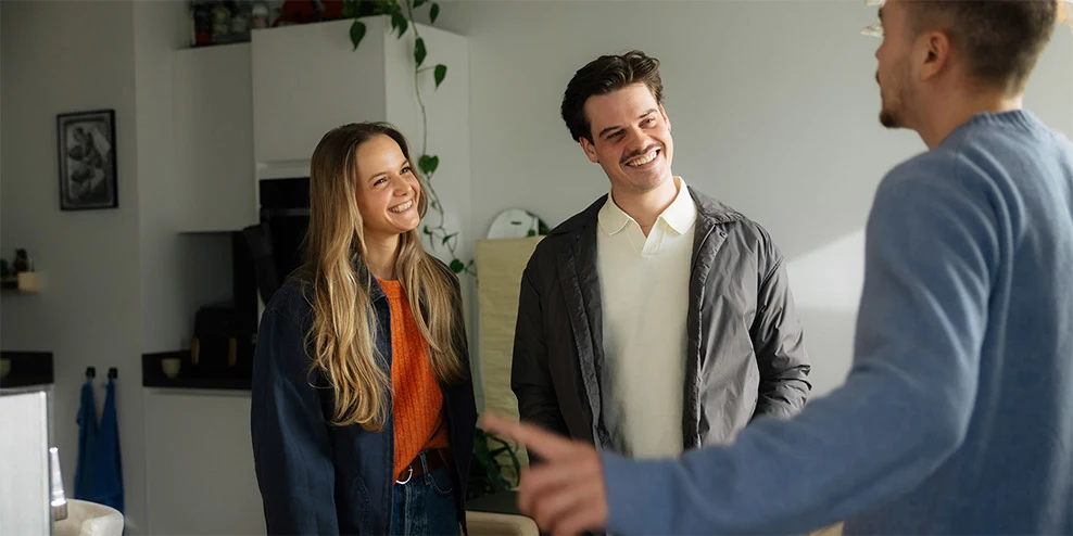 Verkoper praat met twee geïnteresseerden in zijn huis tijdens de NVM Open Huizen Dag