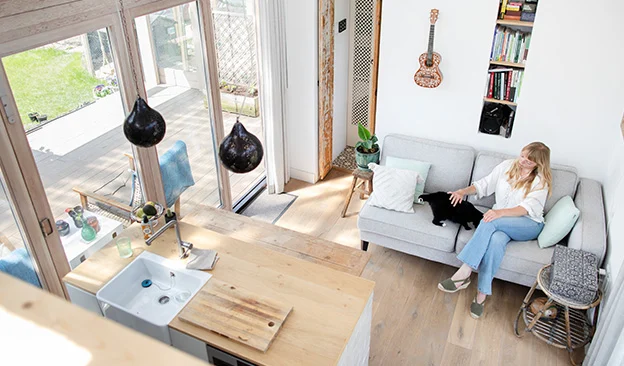 Marjolein Jonker van Tiny Findy zit op de bank in de woonkamer van haar tiny house.