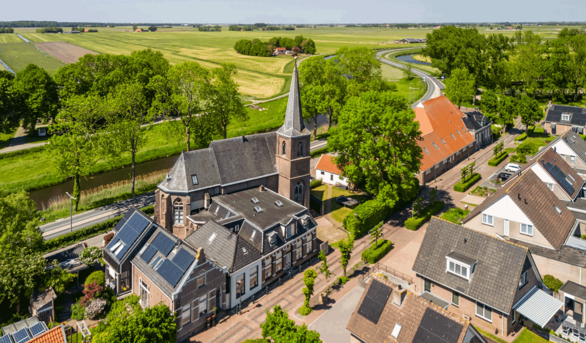 Bovenaanzicht van de gehele kerk, gezien vanuit de lucht, met daaromheen huizen van het dorp Kuinre.