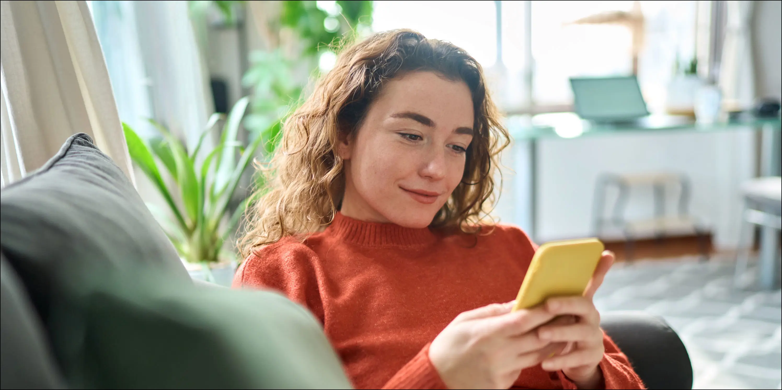 Vrouw kijkt op telefoon naar binnengekomen biedingen op haar huis.