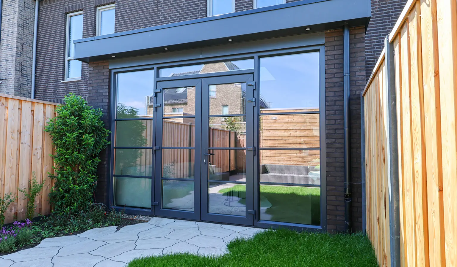 Voorbeeld van een kleine, prefab aanbouw met openslaande deuren aan de achterzijde van een huis.