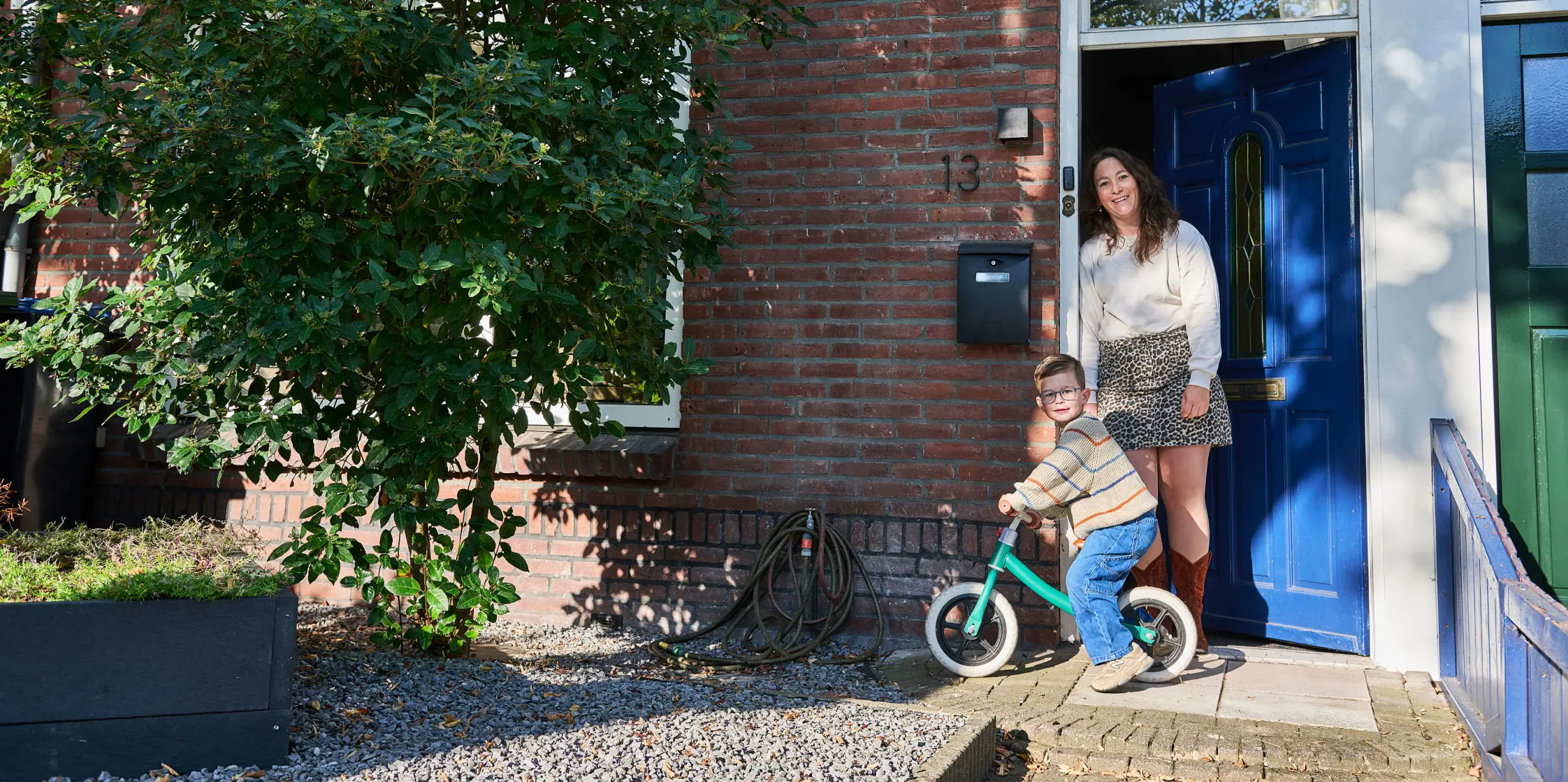 Lieke met haar zoontje Daan voor de blauwe deur van haar tussenwoning in Helmond.