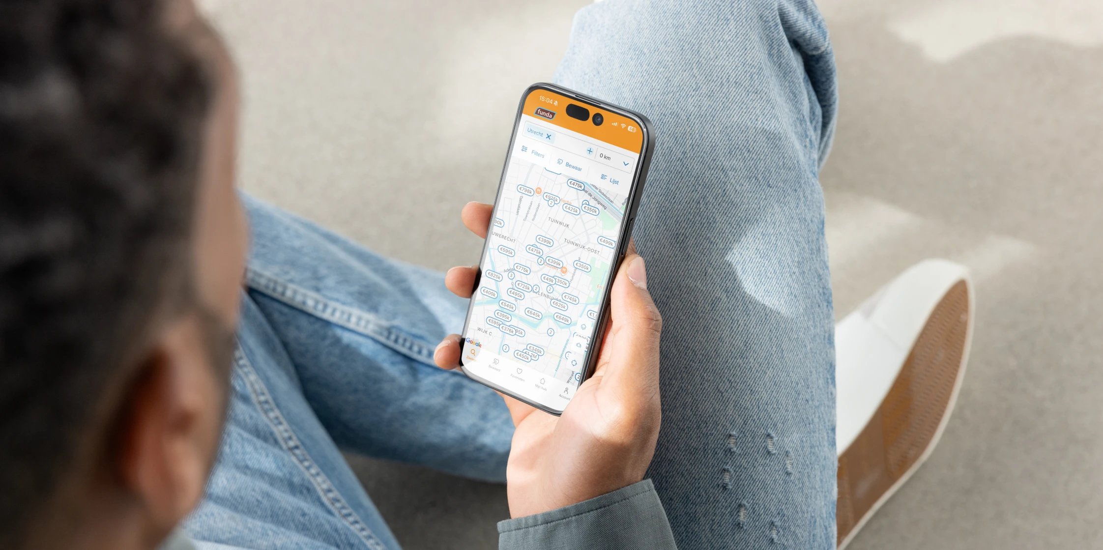 Man bekijkt op zijn telefoon de kaartweergave in de Funda app om huizen te vinden.